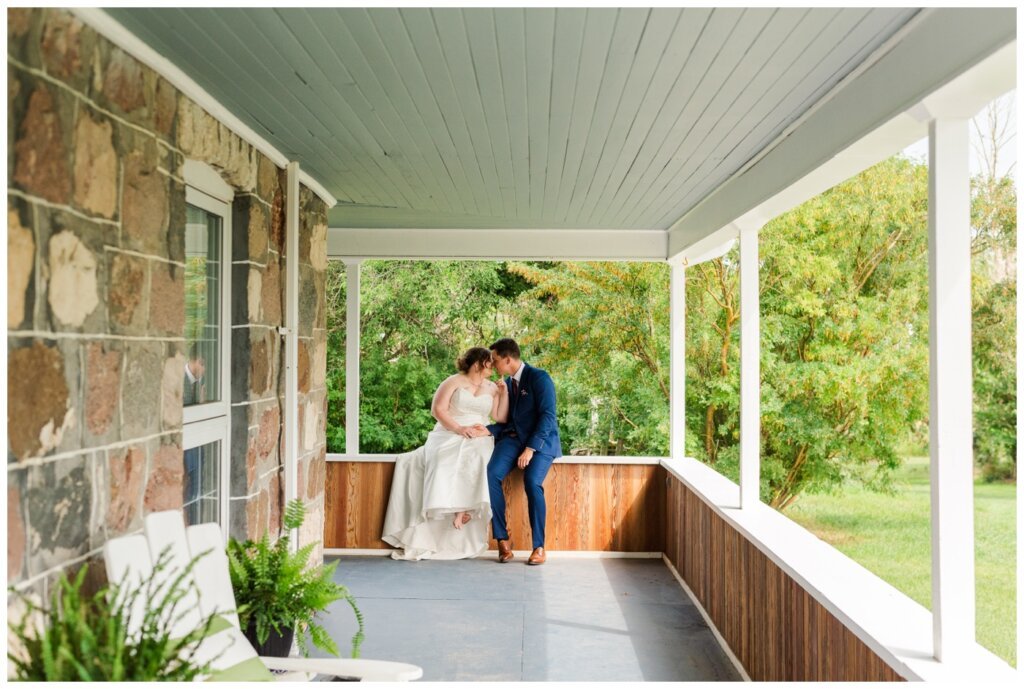 Ben & Megan - 12 - Regina Wedding - Bride & Groom sit on wrap around porch