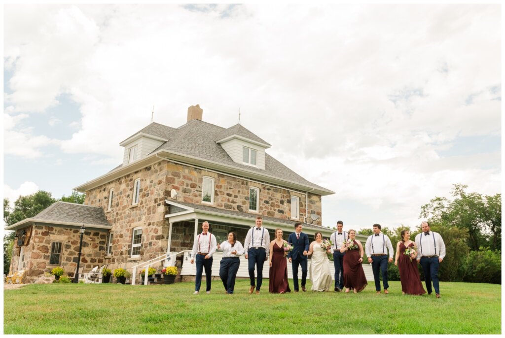Ben & Megan - 17 - Regina Wedding - Bridal party walks in front of hundred year old farm house