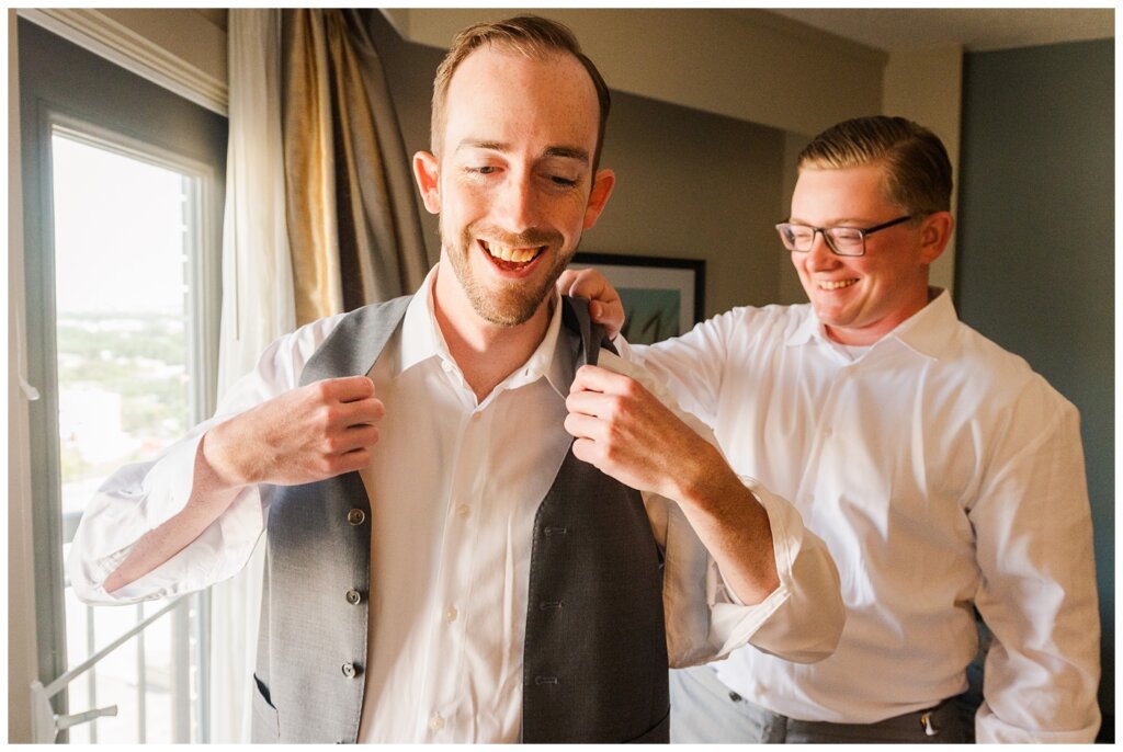 Andrew & Alisha - Regina Wedding Photography - 02 - Groomsmen helps Groom with his vest