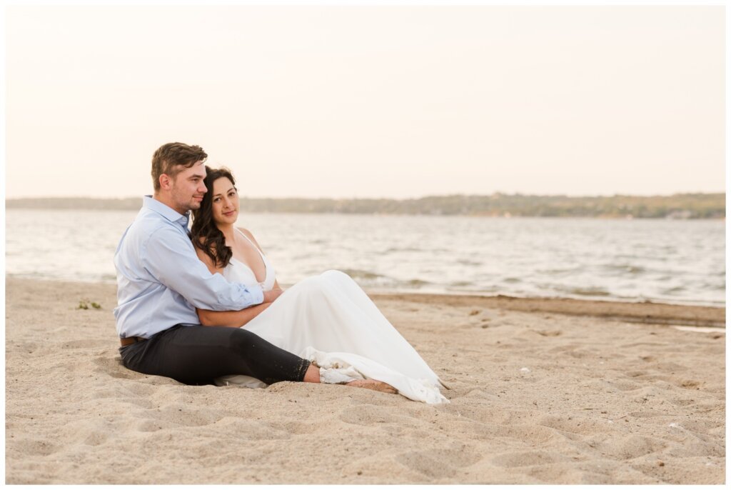 Tris & Jana - 07 - Regina Encore Session - Bride & Groom sit in the sand on the beach