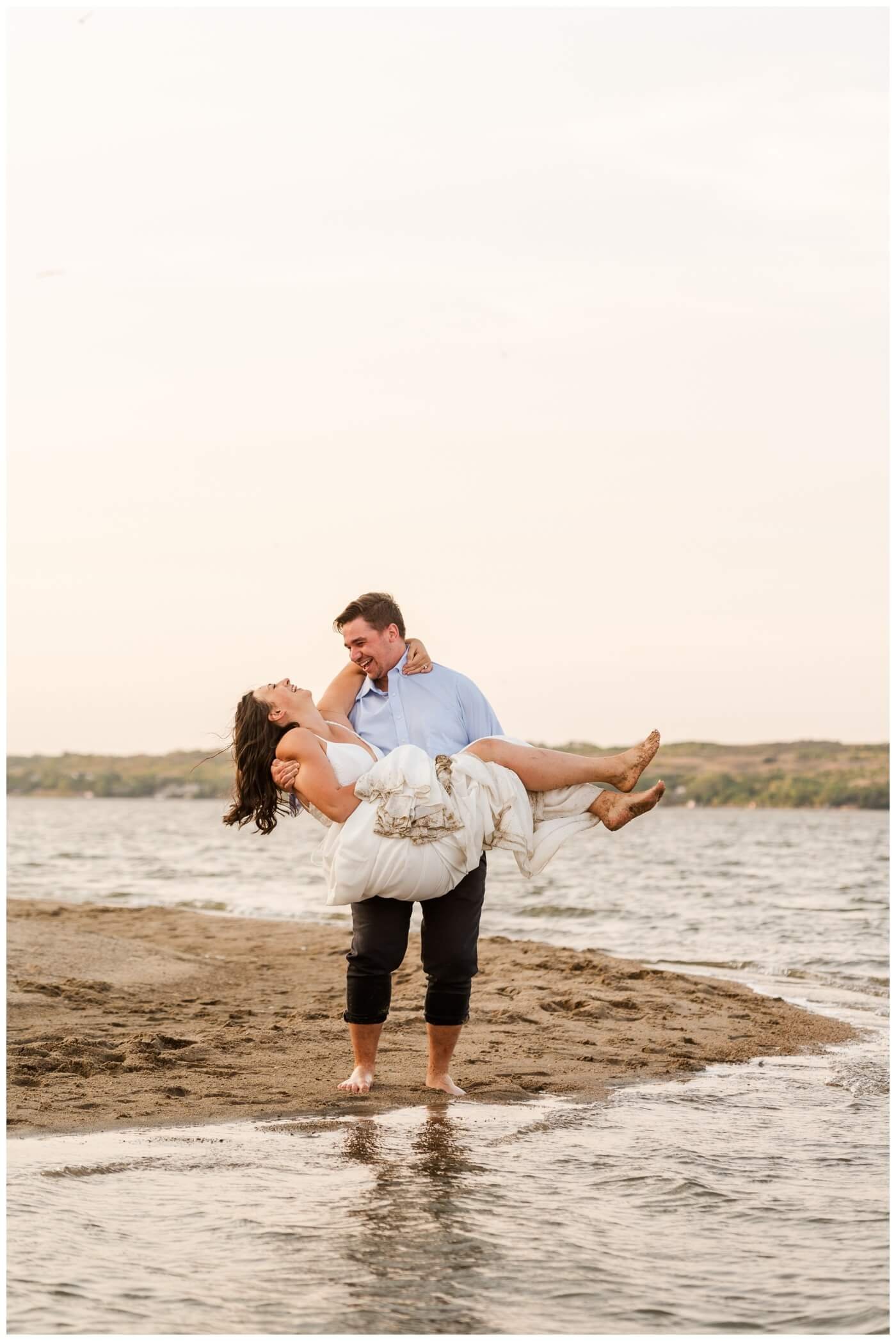 Tris & Jana - 11 - Regina Encore Session - Groom carries his bride down the beach