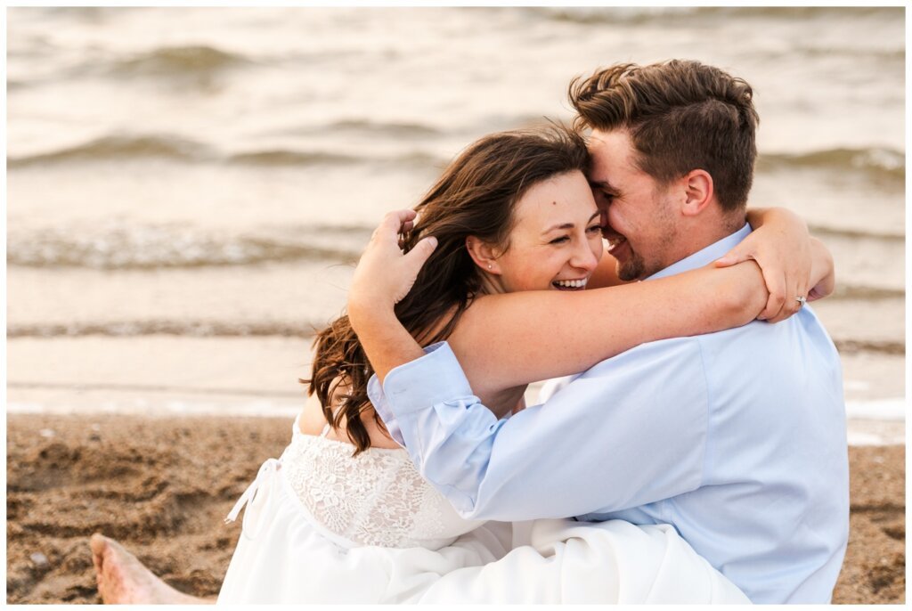 Tris & Jana - 13 - Regina Encore Session - Bride & groom laugh as they sit in the waves