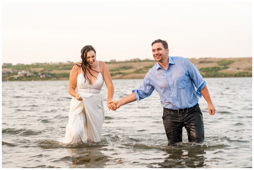 Tris & Jana - 16 - Regina Encore Session - Bride & groom walk out of the lake sopping wet