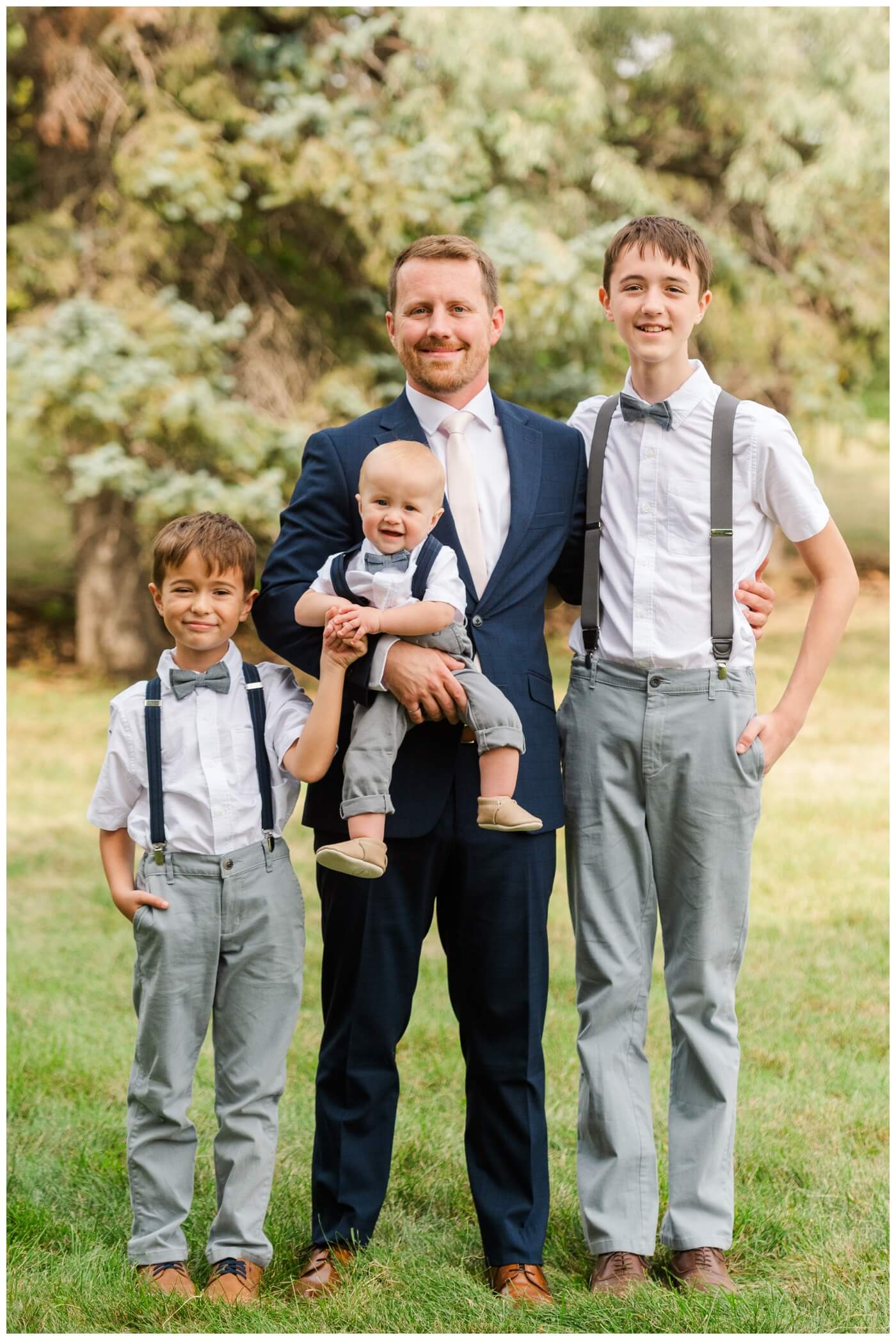 Adam & Caitlin - 02 - Regina Wedding - Groom with his sons in grey pants and suspenders