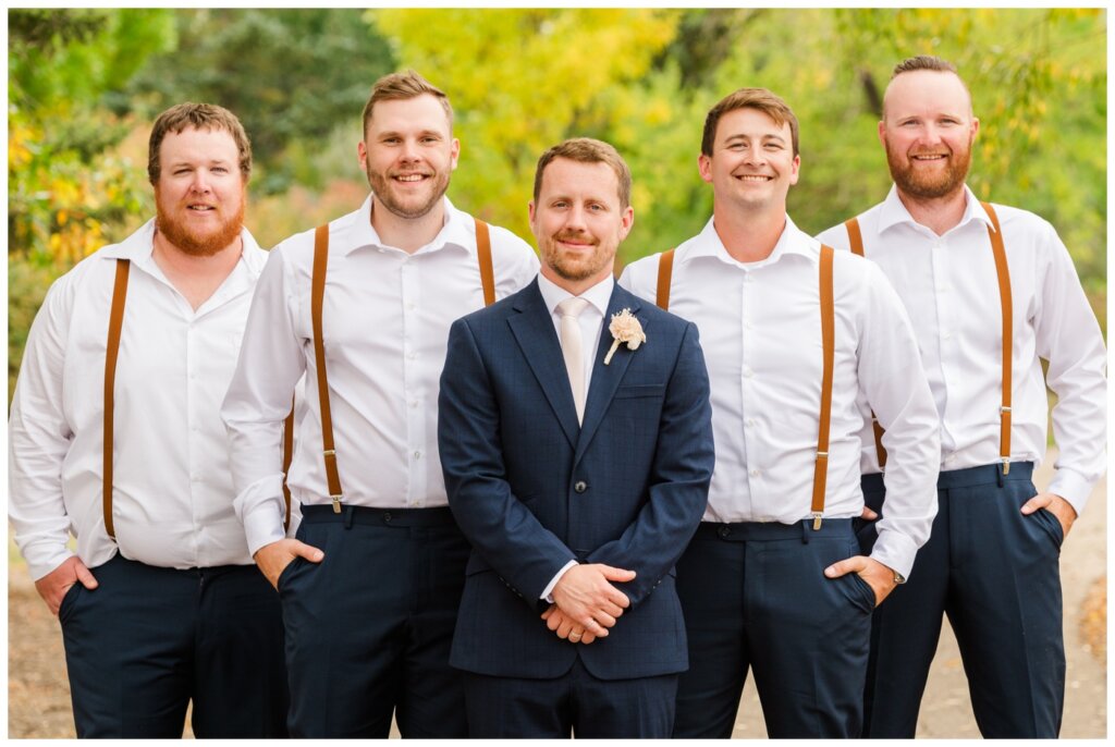 Adam & Caitlin - 20 - Regina Wedding - Groom in navy blue suit with groomsmen in blue pants and tan suspenders