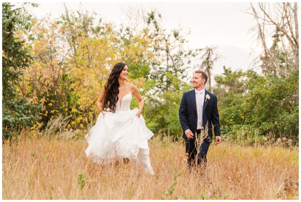 Adam & Caitlin - 30 - Regina Wedding - Bride & Groom run through tall grass