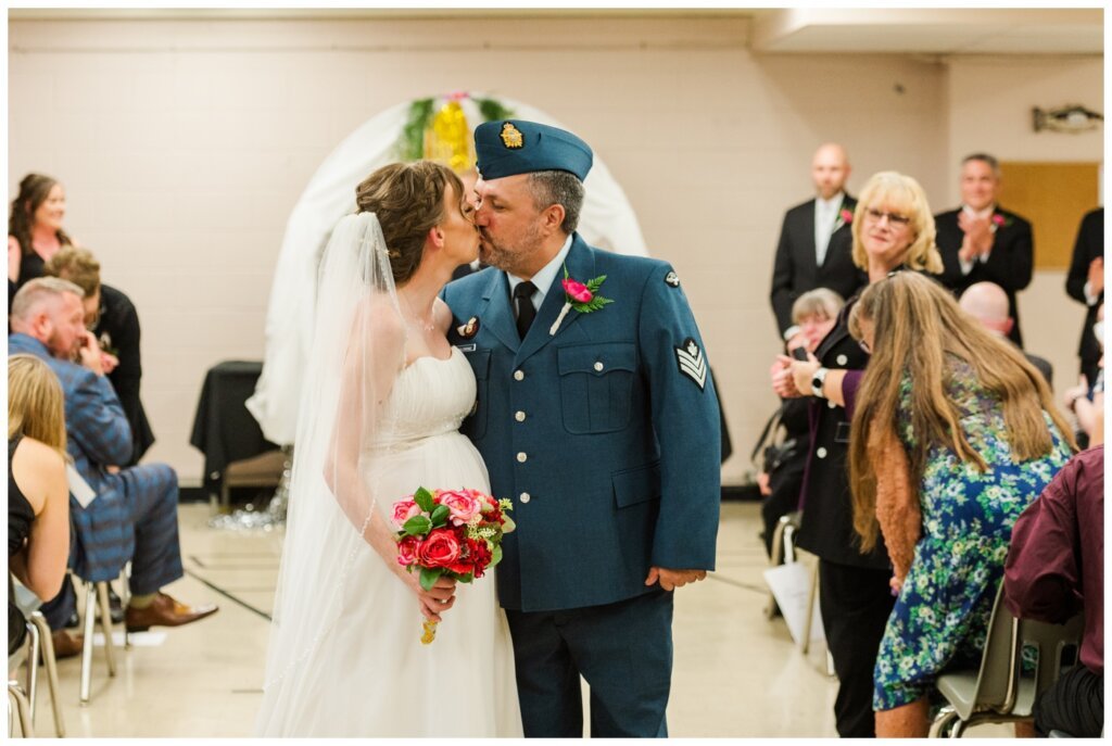 Shawn Jennifer - 20 - Moose Jaw Wedding Bride groom stop for a kiss as they exit the ceremony