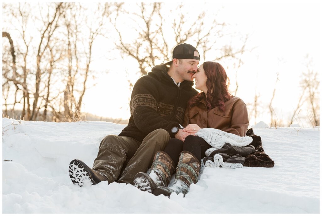 Brett & Brittany - Winter 2023 - Lumsden Valley - 02 - Couple snuggle in a snowbank