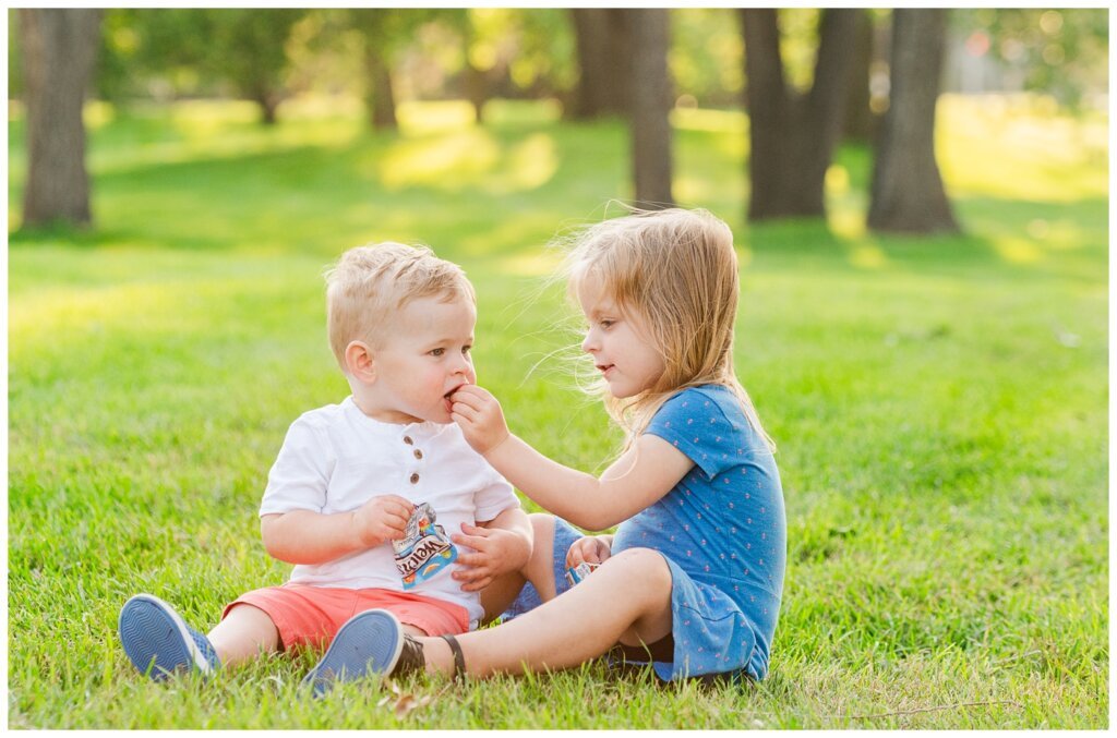 Eyre Family - University of Regina - 17 - Little girl feeds her brother fruit snacks