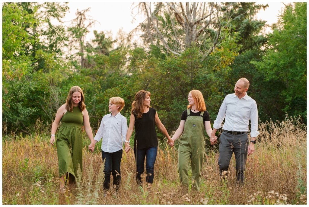 Schoenroth Family - AE Wilson Park - 01 - Family holds hands and walk through tall grass