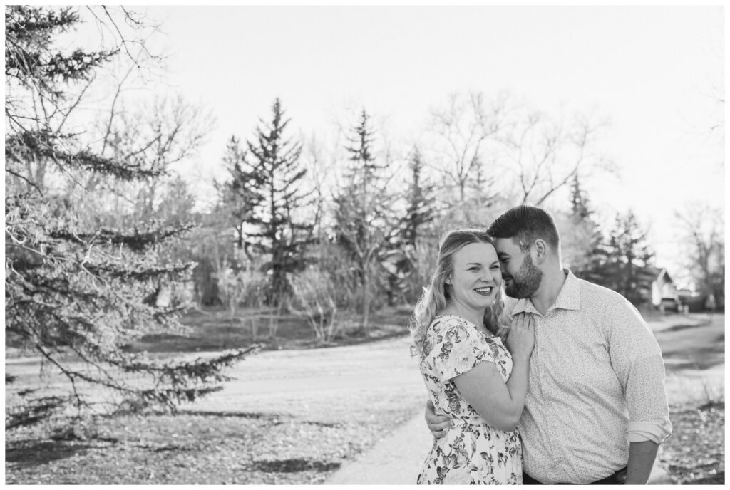 Darcy & Maddie - Regina Engagement - AE Wilson Park - 002 - Groom whispers into his betrotheds ear