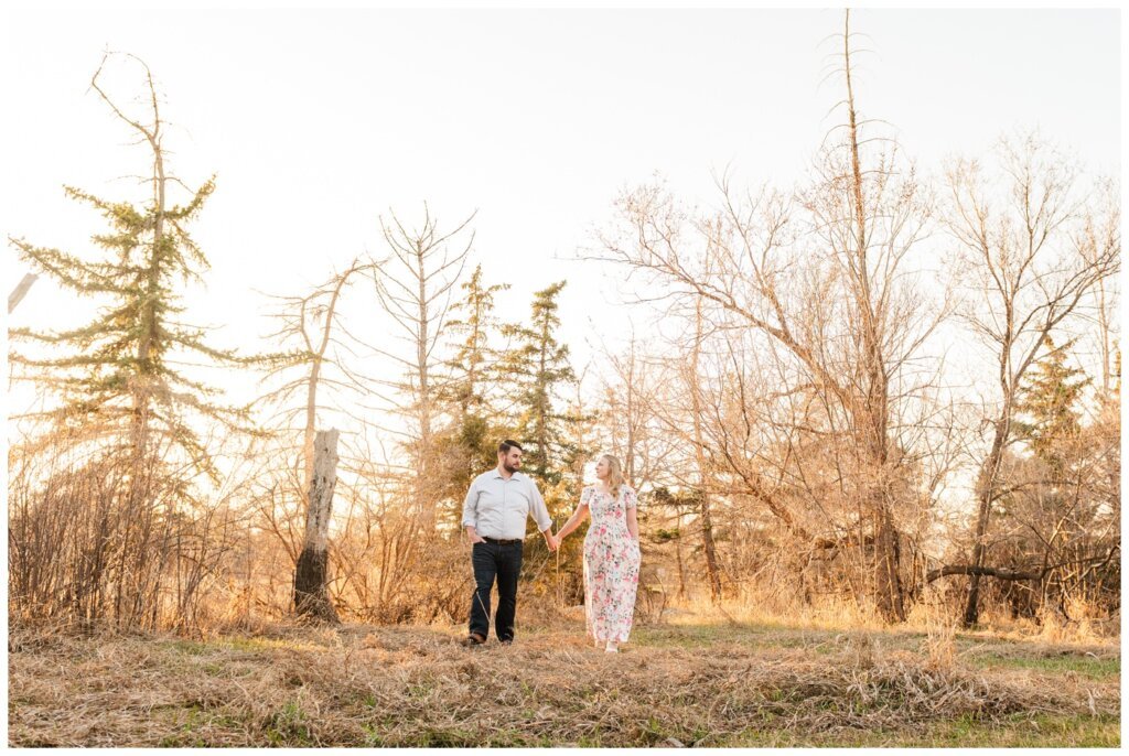 Darcy & Maddie - Regina Engagement - AE Wilson Park - 007 - Couple holds hands in the tall grass