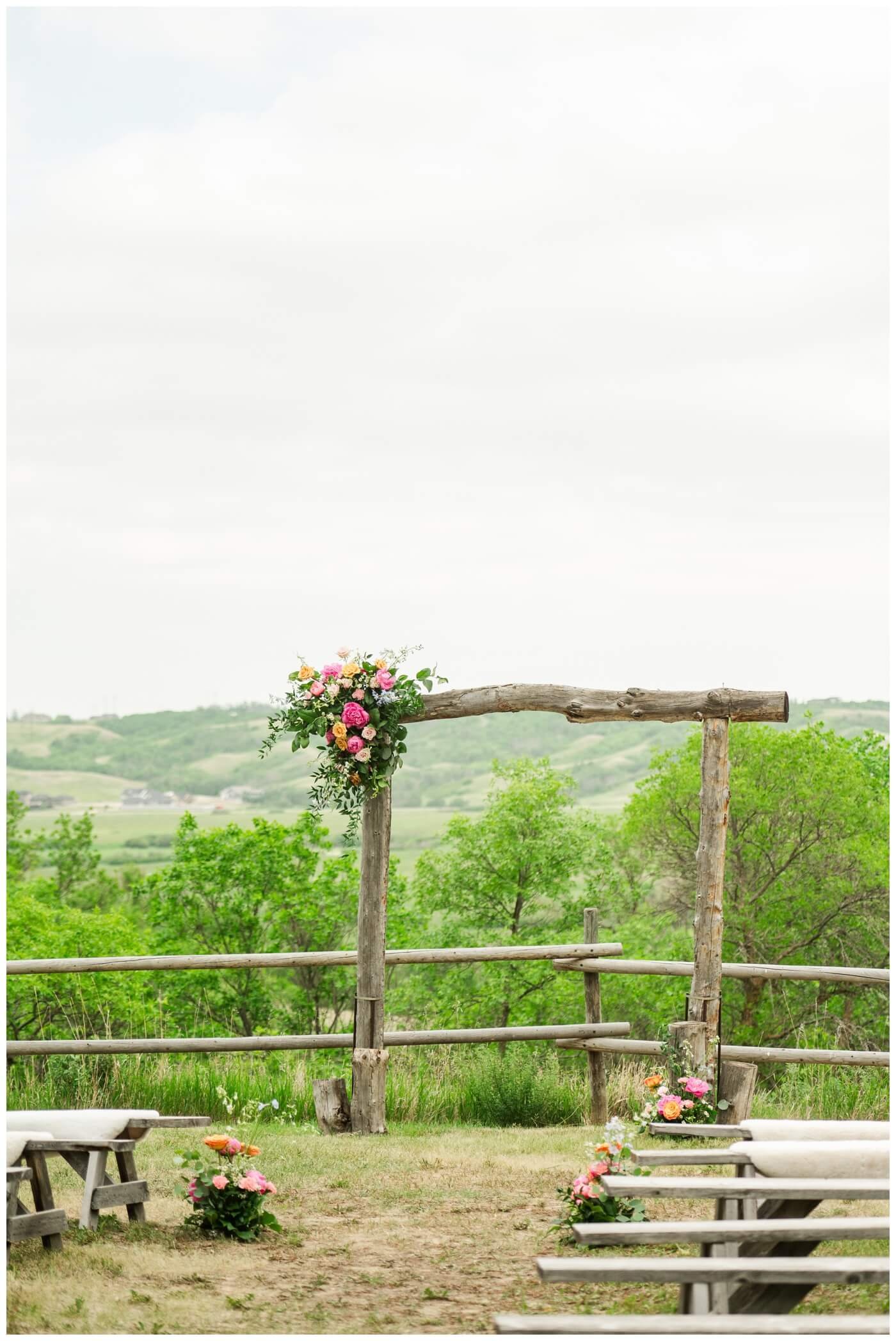 Darcy & Maddie - Regina Summer Wedding - 010 - Goodsman Farm - Rustic alter adorned with bright flowers