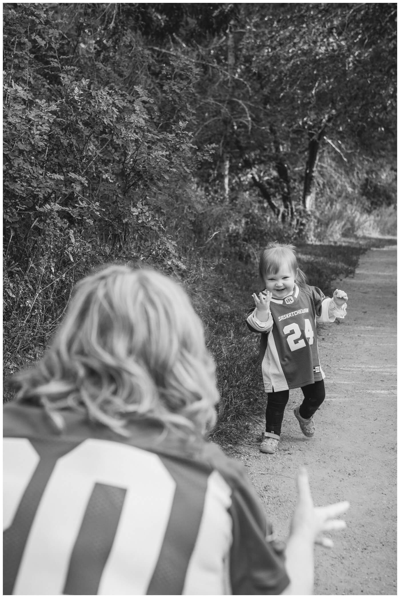 Lindskog Family - AE Wilson Park - 002 - Toddler walks toward her mom in Rider jersey
